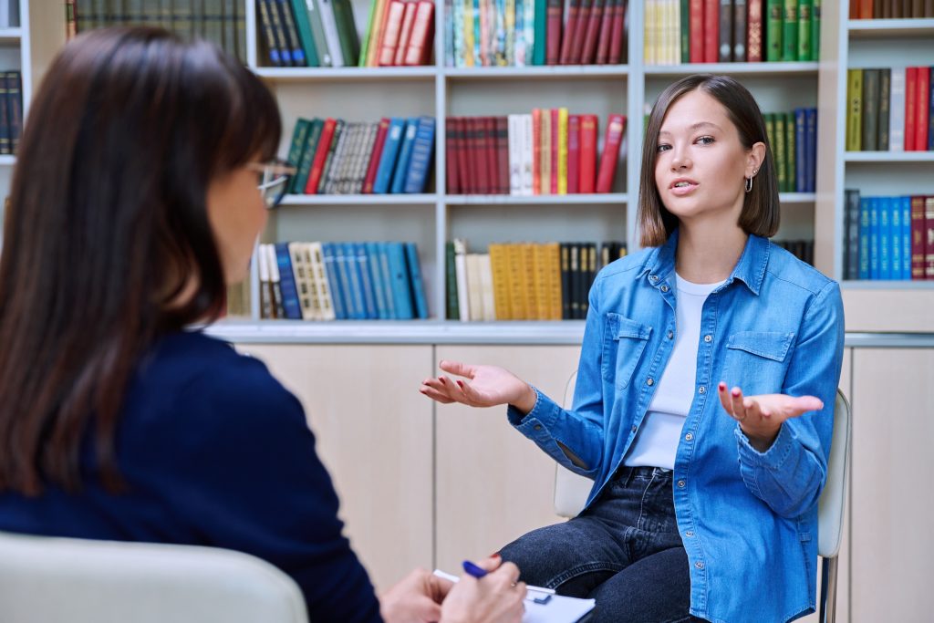 female,student,talking,with,mentor,psychologist,in,office,with,bookshelves